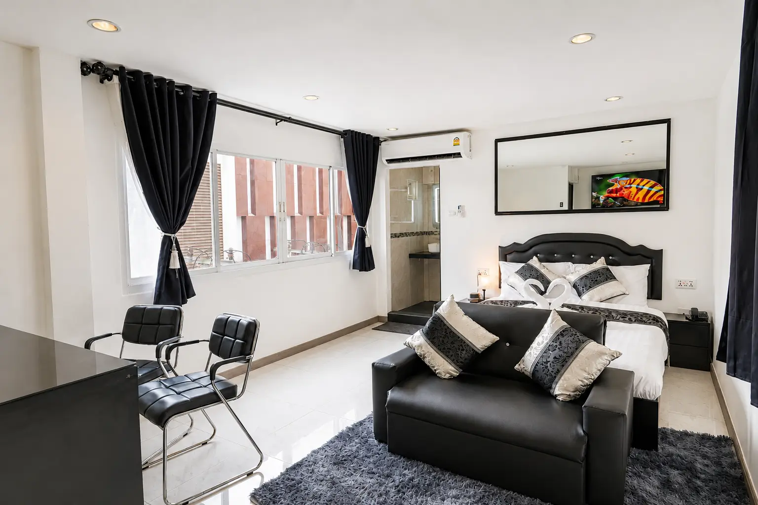 Wide view of the Executive Suite queen bed, sofa, seating and city-facing windows at Thonglor Suites Hotel, Bangkok