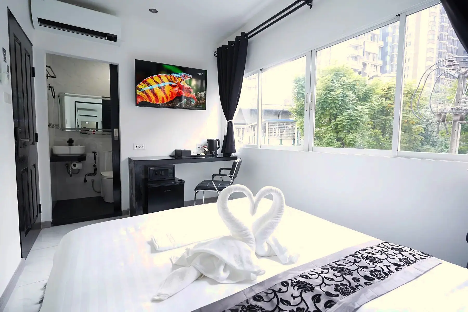 Standard Suite queen bed with towel swans and private bathroom entrance at Thonglor Suites Hotel, Bangkok